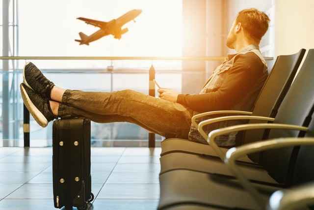 A man sitting at an airport considering the benefits of moving your career abroad.